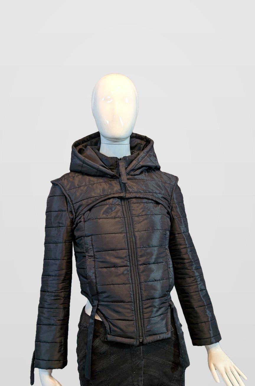 Black Nova Puffer with the hood raised on a mannequin, framed just below the jacket hem and side-strap ends