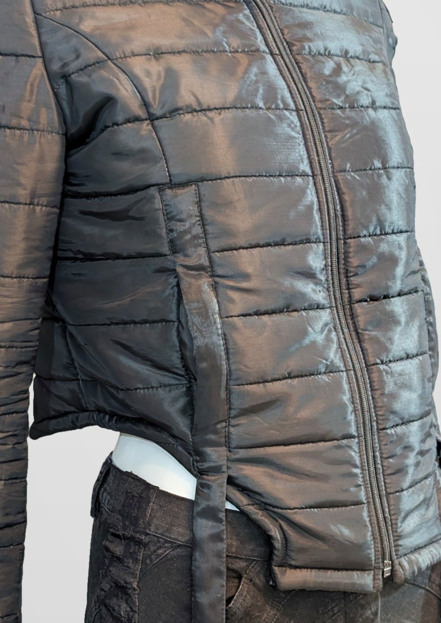 Close detail of the Black Nova Puffer side seam, zip and quilting, framed just below the jacket hem